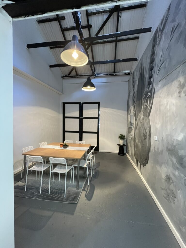 Long view of Studio 6 from the doorway, table and chairs beneath the mural